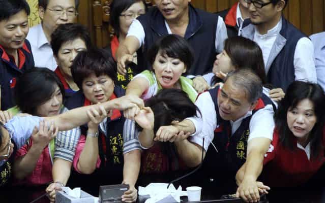 Legislators from Taiwan's ruling Kuomintang party and opposition try to seize the parliament's podium on June 25, 2013. Fighting broke out in Taiwan's parliament as legislators scuffled and threw coffee during a debate on whether a controversial capital gains tax on share trading should be revised less than a year after it was brought in. (Photo by AFP Photo)