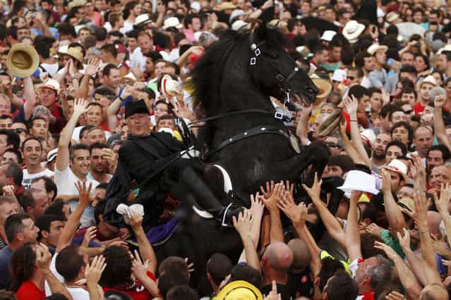 A rider rears up on his horse while surrounded by a cheering crowd during the traditional Fiesta of San Joan (Saint John) in downtown Ciutadella, on the Spanish Balearic Island of Menorca, June 23, 2013. The riders of the horses are representatives of ancient Ciutadella society – nobility, clergy, craftsmen and farmers. (Photo by Enrique Calvo/Reuters)