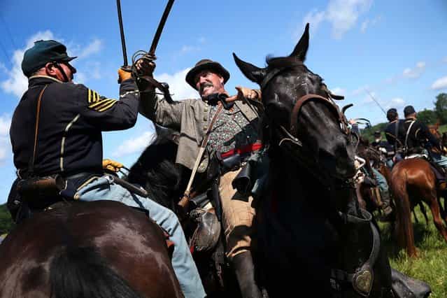 Union and Confederate re-enactors skirmish during a re-enactment of the Battle of Gettysburg in Gettysburg, Pennsylvania, on June 29, 2013. Some 8,000 re-enactors are participating in events marking the 150th anniversary of the July 1-3, 1863 Battle of Gettysburg, considered the turning point in favor of the Union in the American Civil War. Union and Confederate armies suffered a combined total of some 46,000-51,0000 casualties in the battle, the highest of any conflict of the war. (Photo by John Moore/Getty Images)