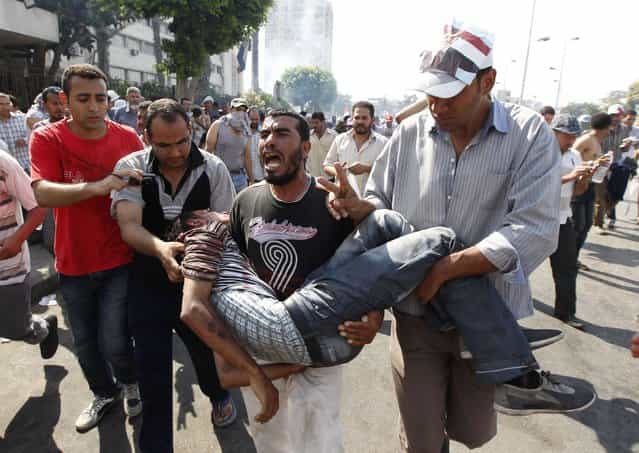 Protesters who support former Egyptian President Mohamed Mursi carry an injured man during clashes outside the Republican Guard building in Cairo July 5, 2013. (Photo by Louafi Larbi/Reuters)