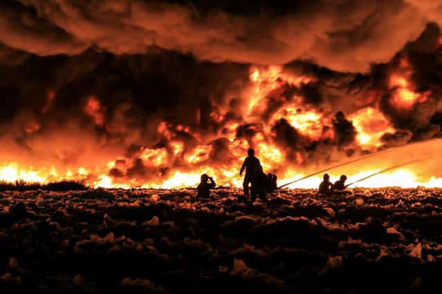 Fire fighters tackle a large blaze at a recycling centre in Smethwick, near Birmingham, central England July 1, 2013 in a handout picture provided by the West Midlands Fire Service. The fire service said they suspected the blaze was started when a Chinese lantern, a collapsible paper lantern lit by a candle, drifted into the centre which holds 100,000 tonnes of recycled paper and plastic. Up to 200 firefighters and 40 fire engines have been deployed. (Photo by Reuters/West Midlands Fire Service)