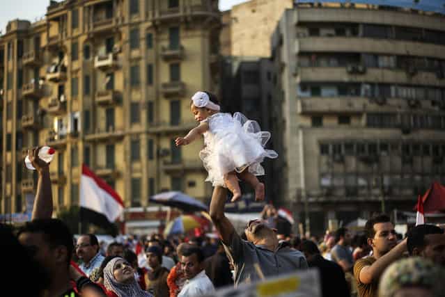 An Egyptian man carries his daughter in Egypt's landmark Tahrir square on July 4, 2013. Egypt's Muslim Brotherhood, from which ousted president Mohamed Morsi hails, denounced a new "police state" after the arrest of Islamist leaders and the closure of satellite channels. (Photo by Gianluigi Guercia/AFP Photo)
