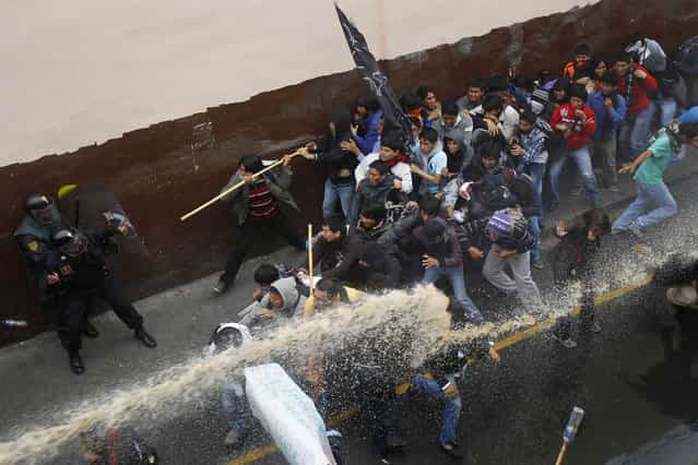 Students clash with riot police during a demonstration against the government in Lima July 4, 2013. Peruvian police fired tear gas at hundreds of students and civil servants in Lima on Thursday as they marched towards Congress to protest reforms that would impose tougher standards on universities and bureaucrats. Protesters lashed out at President Ollanta Humala for proposing the laws, which he says would improve the quality of sluggish government services and a lagging higher-education system. Critics say they would force thousands from their jobs and compromise the autonomy of Peru's universities. (Photo by Enrique Castro-Mendivil/Reuters)