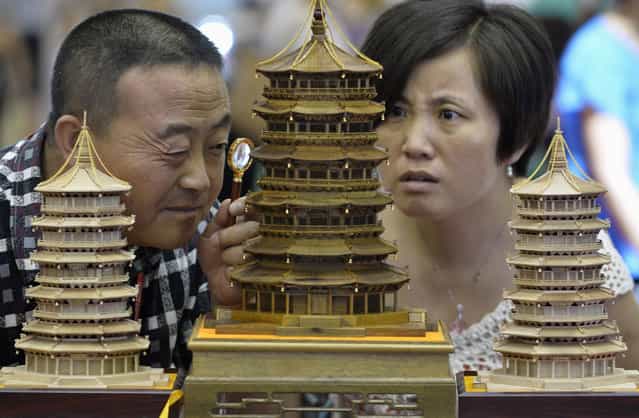 A visitor uses a magnifying glass to look at a handmade wood carving in the shape of a Chinese ancient pavilion at a culture industry exhibition in Taiyuan, Shanxi province July 2, 2013. (Photo by Jon Woo/Reuters)