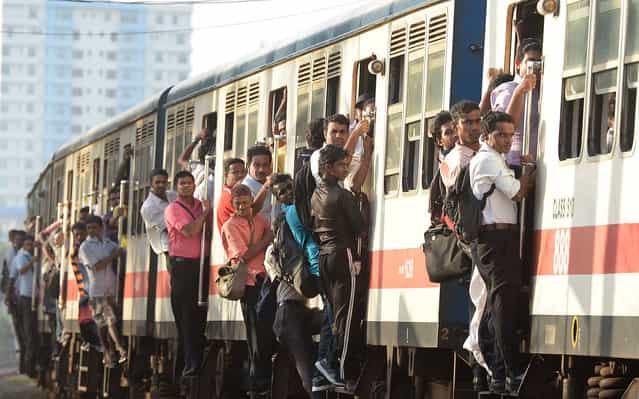 Sri Lankan commuters hold on to the sides of train coaches as they head to work in Colombo on June 29, 2013. (Photo by Lakruwan Wanniarachchi/AFP Photo)