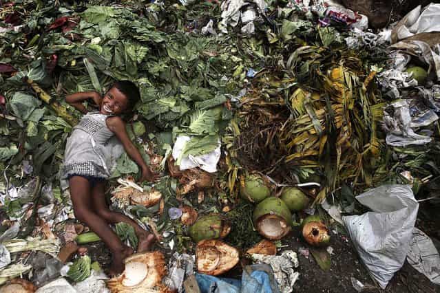 A child plays at a garbage dump near a market in Gauhati, India, on July 4, 2013. The Indian government has decided to come out with an ordinance to give two-thirds of the nation's population the right to 5 kilograms of grains every month at a highly subsidized rate of 1-3 rupees per kg. If implemented, the country’s food security program will be the largest in the world. (Photo by Anupam Nath/Associated Press)