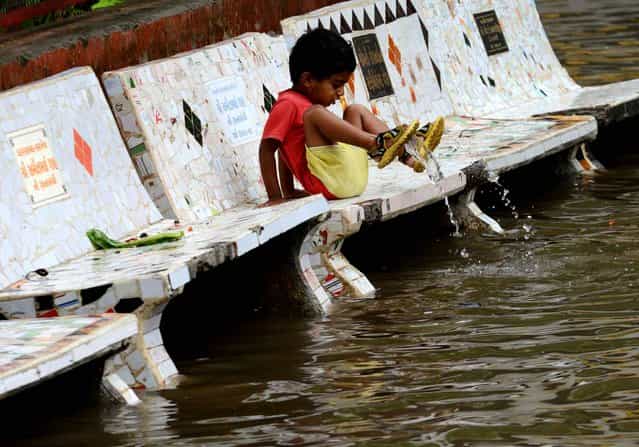 A child at the Shrinand Nagar Residency reacts to floodwaters in Ahmedabad, India, on July 5, 2013. Heavy rains lashed many parts of Gujarat state with the Indian Meteorological Department predicting heavy rains for the next 24 hours. (Photo by Sam Panthaky/Getty Images)