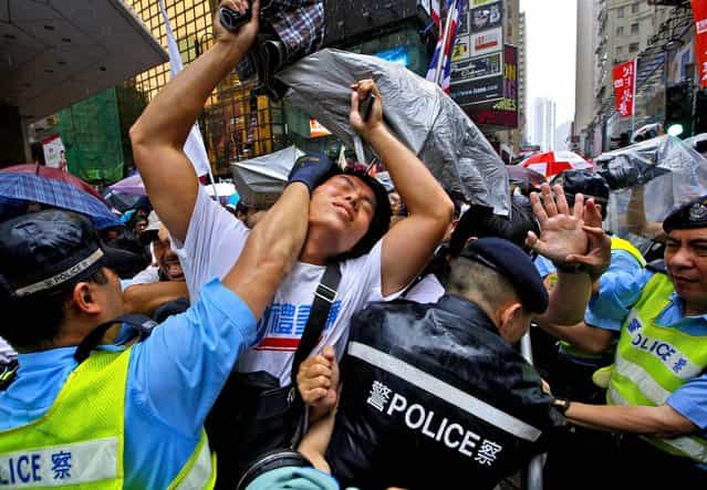 Protesters scuffle with police officers on a downtown street during an annual pro-democracy protest in Hong Kong, on July 1, 2013. Tens of thousands of the protesters demanded their widely disliked Beijing-backed leader resign and pressing for promised democratic reforms so they can choose their own top representative. The march is an annual event that underscores the growing gulf between Hong Kong and the mainland 16 years after the city ceased to be a British colony and came back under Beijing's control. (Photo by Vincent Yu/Associated Press)