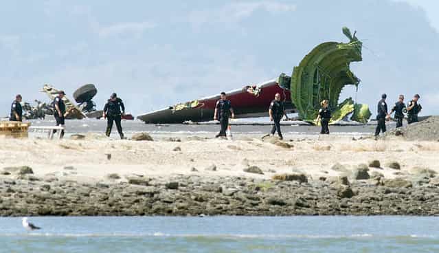 Investigators pass the detached tail and landing gear of Asiana Flight 214 after it crashed at San Francisco International Airport on Saturday, July 6, 2013, in San Francisco. (Photo by Noah Berger/AP Photo)