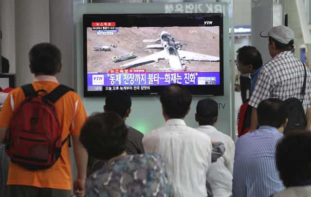 People watch a news program reporting about Asiana Airlines flight 214 which took off from Seoul and crashed while landing at San Francisco International Airport, at Seoul Railway Station in Seoul, South Korea, Sunday, July 7, 2013. The writing on the screen reads [Fire on the ceiling of the airplane]. (Photo by Ahn Young-joon/AP Photo)