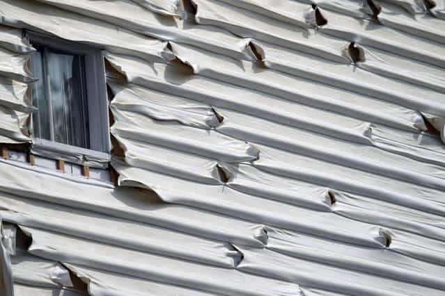 Melted siding on a home is seen near the scene of a train derailment in Lac Megantic, Quebec, July 7, 2013. (Photo by Christinne Muschi/Reuters)