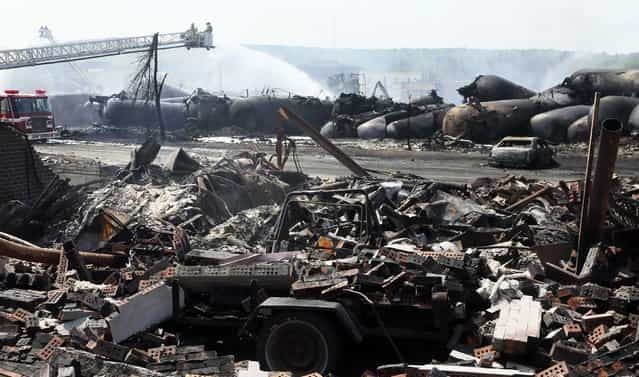 The remains of a home lie in rubble as firefighters continue working on the scene of a train derailment in Lac Megantic, Quebec, July 7, 2013. A driverless freight train carrying tankers of petroleum products derailed at high speed and exploded into a giant fireball in the middle of the small Canadian town of Lac-Megantic early on Saturday, destroying dozens of buildings and leaving an unknown number of people feared missing. (Photo by Christinne Muschi/Reuters)