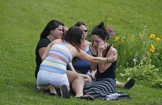 A woman comforts her friend while they sit on the grass at the Polyvalente Montignac, a school sheltering people who were forced to leave their houses after the explosion, in Lac-Megantic, on July 7, 2013. (Photo by Mathieu Belanger/Reuters)