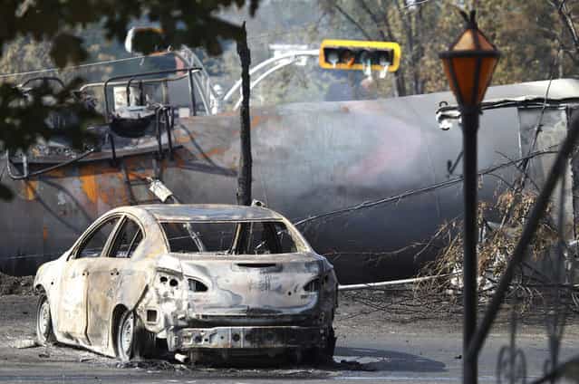 A burned vehicle sits near the wreckage of a train car and a melted traffic light, after a train derailment and fire in Lac-Megantic, on July 7, 2013. (Photo by Christinne Muschi/Reuters)