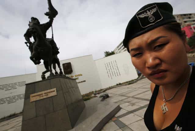 Uranjargal, a leader of the Mongolian neo-Nazi group Tsagaan Khass, stands next to a statue of Chingunjav, a Mongolian national hero, in Ulan Bator June 22, 2013. The group has rebranded itself as an environmentalist organisation fighting pollution by foreign-owned mines, seeking legitimacy as it sends Swastika-wearing members to check mining permits. Over the past years, ultra-nationalist groups have expanded in the country and among those garnering attention is Tsagaan Khass, which has recently shifted its focus from activities such as attacks on women it accuses of consorting with foreign men to environmental issues, with the stated goal of protecting Mongolia from foreign mining interests. This ultra-nationalist group was founded in the 1990s and currently has 100-plus members. (Photo by Carlos Barria/Reuters)