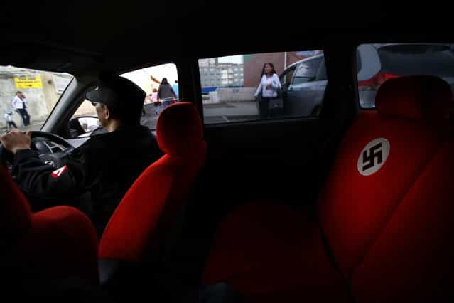 A swastika is seen on the seat of a car belonging to Ariunbold, leader of the Mongolian neo-Nazi group Tsagaan Khass, as he drives along a busy street in Ulan Bator June 22, 2013. The group has rebranded itself as an environmentalist organisation fighting pollution by foreign-owned mines, seeking legitimacy as it sends Swastika-wearing members to check mining permits. Over the past years, ultra-nationalist groups have expanded in the country and among those garnering attention is Tsagaan Khass, which has recently shifted its focus from activities such as attacks on women it accuses of consorting with foreign men to environmental issues, with the stated goal of protecting Mongolia from foreign mining interests. This ultra-nationalist group was founded in the 1990s and currently has 100-plus members. (Photo by Carlos Barria/Reuters)