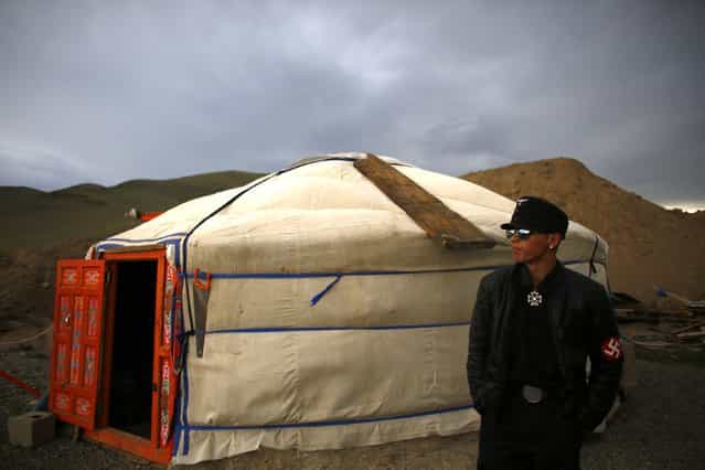 A member of the Mongolian neo-Nazi group Tsagaan Khass stands next to a 'ger', a traditional Mongolian tent, at a quarry, where they questioned a worker, southwest of Ulan Bator June 23, 2013. The group has rebranded itself as an environmentalist organisation fighting pollution by foreign-owned mines, seeking legitimacy as it sends Swastika-wearing members to check mining permits. Over the past years, ultra-nationalist groups have expanded in the country and among those garnering attention is Tsagaan Khass, which has recently shifted its focus from activities such as attacks on women it accuses of consorting with foreign men to environmental issues, with the stated goal of protecting Mongolia from foreign mining interests. This ultra-nationalist group was founded in the 1990s and currently has 100-plus members. (Photo by Carlos Barria/Reuters)