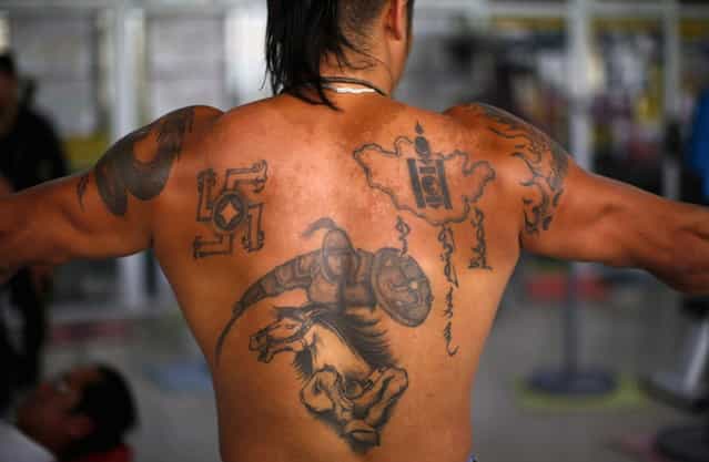 Tattoos are seen on the back of a member of a self-described skinhead group as he trains at a gym in Ulan Bator June 22, 2013. Over the past years, ultra-nationalist groups have expanded in the country and among those garnering attention is Tsagaan Khass, which has recently shifted its focus from activities such as attacks on women it accuses of consorting with foreign men to environmental issues, with the stated goal of protecting Mongolia from foreign mining interests. This ultra-nationalist group was founded in the 1990s and currently has 100-plus members. (Photo by Carlos Barria/Reuters)