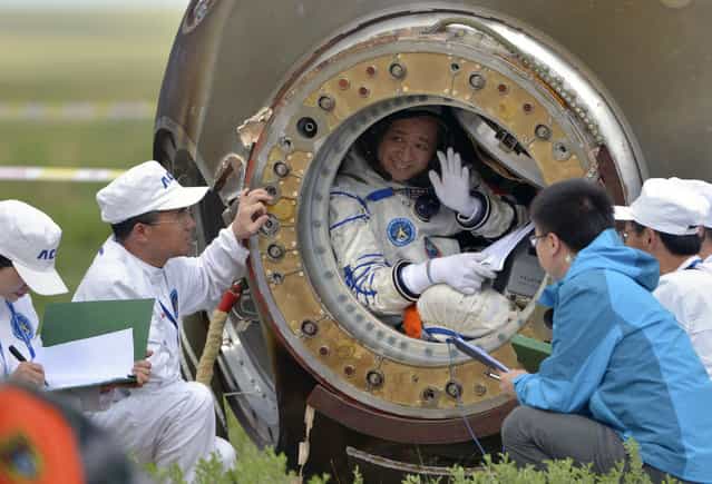 Chinese astronaut Nie Haisheng waves before stepping out of the re-entry capsule of China's Shenzhou-10 spacecraft after it landed in Inner Mongolia Autonomous Region, on June 26, 2013. Three Chinese astronauts returned to Earth on Wednesday, touching down after a successful 15-day mission in which they docked with a space laboratory. (Photo by Reuters/China Daily via The Atlantic)