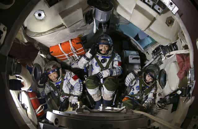 Chinese astronauts (from left) Zhang Xiaoguang, Nie Haisheng and Wang Yaping salute in a re-entry capsule during a training at Beijing Aerospace City in Beijing, on April 29, 2013. (Photo by Reuters/Stringer via The Atlantic)