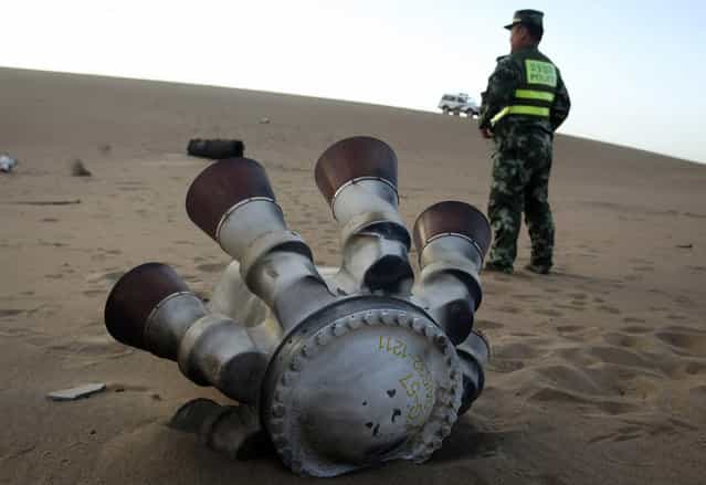 A policeman stands guard next to a component of the Shenzhou-10 manned spacecraft which was found in Badain Jaran Desert after the launch, in Alxa League, Inner Mongolia Autonomous Region, on June 12, 2013. (Photo by Reuters/Stringer via The Atlantic)