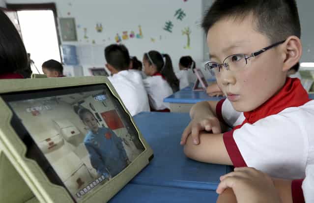 A student looks at an iPad as his class watches a live broadcast of a lecture given by Shenzhou-10 spacecraft astronauts on the Tiangong-1 space module, at a primary school in Quzhou, Zhejiang province, on June 20, 2013. (Photo by Reuters/Stringer via The Atlantic)