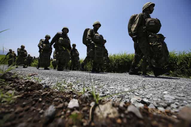 Japanese Ground Self-Defense Force's 1st Airborne Brigade soldiers walks toward to a CH-47 helicopter for parachute drop training during their military drill at Higashifuji training field in Susono, west of Tokyo, July 8, 2013. Japan faces increasingly serious threats to its security from China and North Korea, a defence ministry report said on Tuesday, as ruling politicians call for the military to beef up its ability to respond to such threats. Picture taken July 8, 2013. (Photo by Issei Kato/Reuters)
