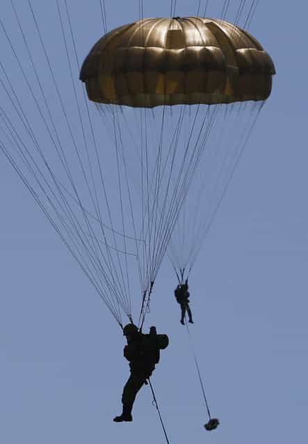 Japanese Ground Self-Defense Force's 1st Airborne Brigade soldiers parachutes down from a CH-47 helicopter during their military drill at Higashifuji training field in Susono, west of Tokyo, July 8, 2013. Japan faces increasingly serious threats to its security from an assertive China and an unpredictable North Korea, a defence ministry report said on Tuesday, as ruling politicians call for the military to beef up its ability to respond to such threats. (Photo by Issei Kato/Reuters)
