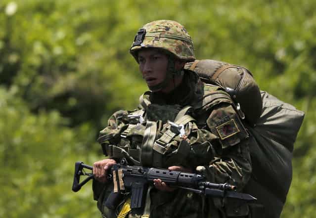 A Japanese Ground Self-Defense Force's 1st Airborne Brigade soldier walks toward a staging post after parachuting during their military drill at Higashifuji training field in Susono, west of Tokyo, July 8, 2013. Japan faces increasingly serious threats to its security from an assertive China and an unpredictable North Korea, a defence ministry report said on Tuesday, as ruling politicians call for the military to beef up its ability to respond to such threats. (Photo by Issei Kato/Reuters)