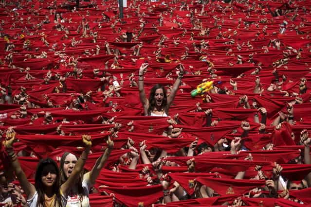 Participants hold red scarves as they celebrate the [Chupinazo] marking the start at noon sharp of the San Fermin Festival at Castle square in Pamplona, northern Spain on July 6, 2013. Ten of thousands of people packed Pamplona's streets for a drunken kick-off to Spain's best-known fiesta: the nine-day San Fermin bull-running festival. (Photo by Pedro Armestre/AFP Photo)