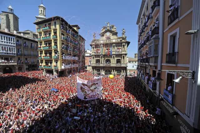 Participants hold red scarves as they celebrate the [Chupinazo] to mark the start at noon sharp of the San Fermin Festival on July 6, 2013 in front of the Town Hall of Pamplona, northern Spain. Tens of thousands of people packed Pamplona's streets for a drunken kick-off to Spain's best-known fiesta: the nine-day San Fermin bull-running festival. (Photo by Rafa Rivas/AP Photo)