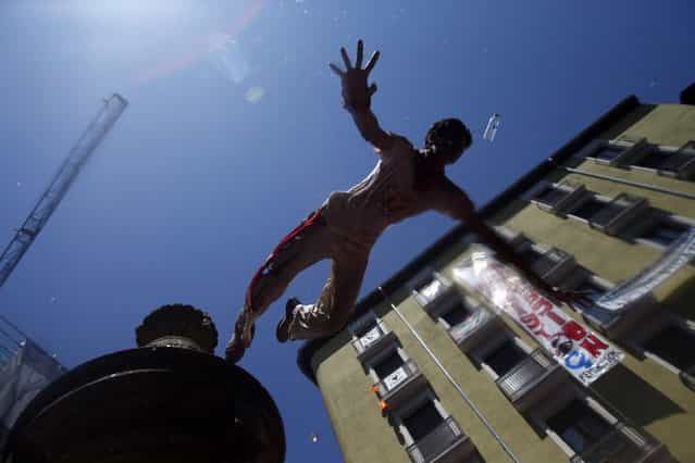 A reveller jumps from a fountain at the Plaza de Navarreria as he is sprayed with water during the start of the San Fermin festival in Pamplona July 6, 2013. The beginning of the festival, known as the Chupinazo, was postponed for 20 minutes while authorities removed a Basque flag hanging in front of the town hall. The annual San Fermin festival, famous for the running of the bulls event, started on Saturday and runs until July 14. (Photo by Susana Vera/Reuters)