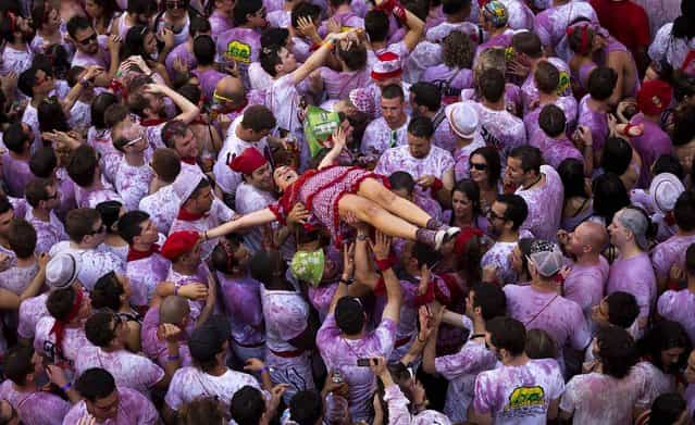 Revelers hold up a girl during the launch of the [Chupinazo] rocket, to celebrate the official opening of the 2013 San Fermin fiestas. (Photo by Daniel Ochoa de Olza/Associated Press)