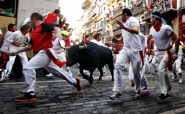 Revelers run in front of a Valdefresno ranch fighting bull. (Photo by Daniel Ochoa de Olza/Associated Press)