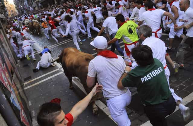 Revelers go after Alcurrucen ranch fighting bulls on the Estafeta corner. (Photo by Alvaro Barrientos/Associated Press)