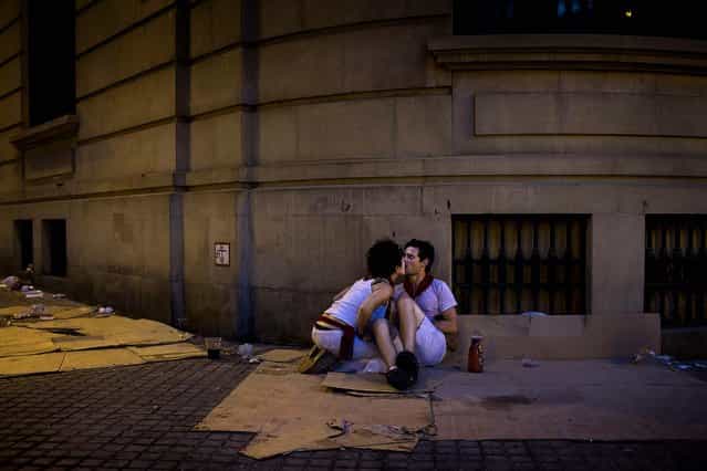 Revelers kiss on a street during the San Fermin fiestas. (Photo by Daniel Ochoa de Olza/Associated Press)