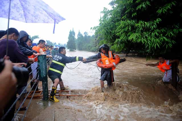 Firefighters use a rope to help a woman (C) walk across floodwaters after heavy rainfalls hit Dujiangyan, Sichuan province July 9, 2013. At least one person died and 15 others were missing in southwest China's Sichuan Province as of Tuesday evening after severe rainstorms battered the region, including some quake-stricken areas, Xinhua News Agency reported. (Photo by Reuters/China Daily)