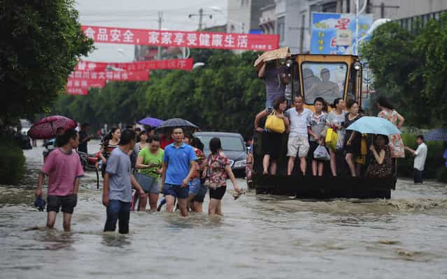 Residents are evacuated through a flooded street by an excavator in Guanghan city in southwestern China's Sichuan province Tuesday July 9, 2013. (Photo by AP Photo)
