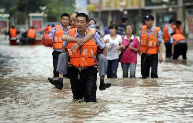A policeman carries a man on his back as he walks on a flooded street after heavy rainfalls hit Chengdu, Sichuan province, July 9, 2013. (Photo by Reuters/China Daily)