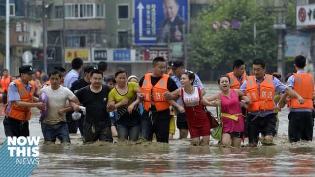 Policemen hold the arms of residents as they walk on a flooded street after heavy rainfall hit Chengdu, Sichuan province, July 9, 2013. (Photo by Reuters/Stringer)