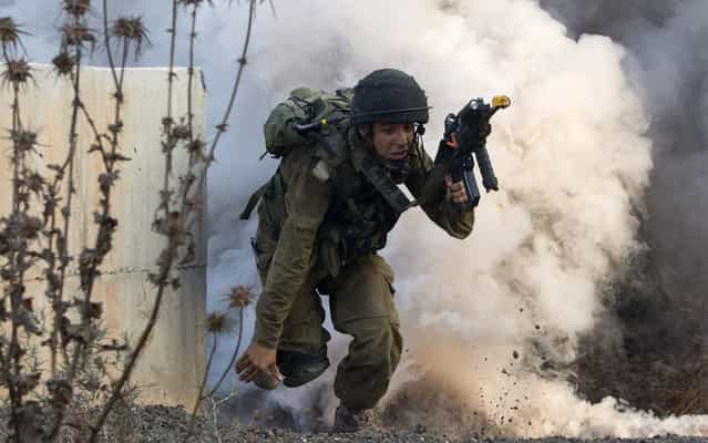 An Israeli infantry soldier from the Kfir Brigade takes part in a drill in urban warfare simulating a combat mission with Lebanon's Hezbollah at the Israeli army base of Elyakim in northern Israel on July 11, 2013. Israeli military built the training base at Elyakim to train soldiers on how to fight Hezbollah as Israel bolsters security along its border with Syria, where Hezbollah militants are reportedly fighting alongside government forces against rebels. (Photo by Jack Guez/AFP Photo)