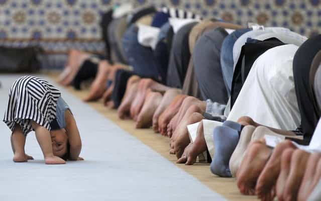 A child is seen near members of the Muslim community attending midday prayers at Strasbourg Grand Mosque in Strasbourg on the first day of Ramadan July 9, 2013. The Grand Mosque of Paris has fixed the first day of Ramadan as Wednesday, splitting with the French Council of Muslim Religion (Conseil Francais du Culte Musulman or CFCM), which determined it would begin on Tuesday. (Photo by Vincent Kessler/Reuters)