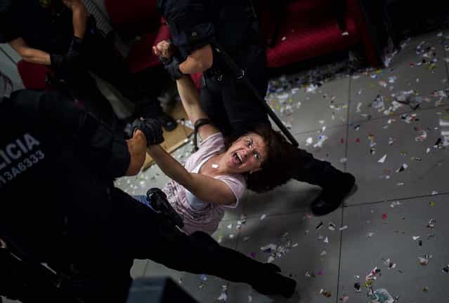An activist of the Mortgage Victims' Platform is carried by police officers after occupying a bank as part of a protest to support a neighbor who is facing an eviction process in Barcelona, on July 10, 2013. With 26 percent unemployment, Spain is struggling to emerge from its second recession in just over three years as the economy battles to recover from the collapse of its once-booming real estate sector. (Photo by Emilio Morenatti/Associated Press)