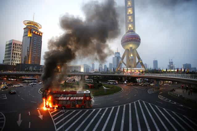 A double-decker tourism bus is seen on fire in from of the Oriental Pearl Tower in the Pudong financial district of Shanghai July 8, 2013. Passengers were seen walking away from the bus which burst into flames during rush hour at one of the busiest intersections in the city. (Photo by Carlos Barria/Reuters)