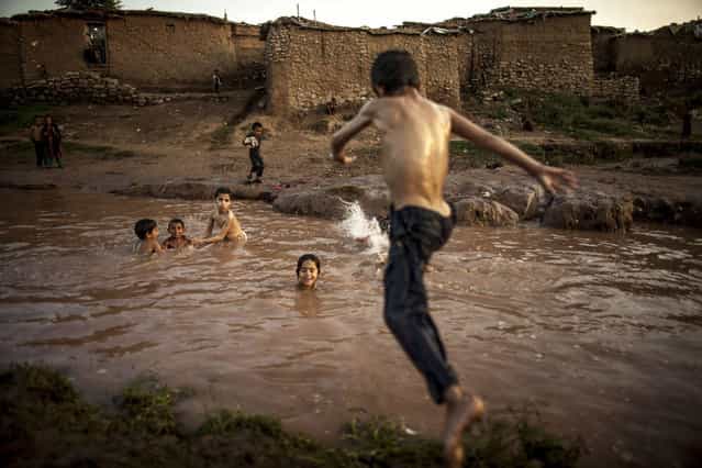 A boy, whose his family fled military operations in the western tribal area, jumps into a stream in a slum on the outskirts of Islamabad July 8, 2013. (Photo by Zohra Bensemra/Reuters)