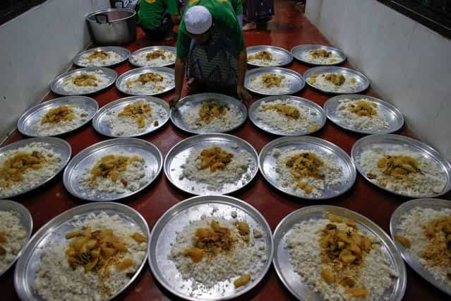 A Rohingya Muslim illegal immigrant prepares plates of food at the Immigration Detention Centre during the holy month of Ramadan in Kanchanaburi province July 10, 2013. More than a hundred Rohingya Muslims gathered to pray and break fast as they welcome the first day of Ramadan in Thailand. The stateless people arrived in Thailand earlier in January this year after fleeing a bloody conflict between the Buddhist and Muslims in Myanmar's western Rakhine State. (Photo by Athit Perewongmetha/Reuters)