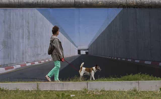 A woman walks past a picture showing a border fortification in the West Bank by German photographer Kai Wiedenhoefer at the former Berlin Wall in Berlin, July 11, 2013. Wiedenhoefer's Wall on Wall project consists of panoramic pictures of eight border walls that separate people in different parts of the world. The pictures are currently displayed as 9x3 metre prints that Wiedenhoefer has pasted onto the longest remaining stretch of the former Berlin Wall border fortification. (Photo by Thomas Peter/Reuters)