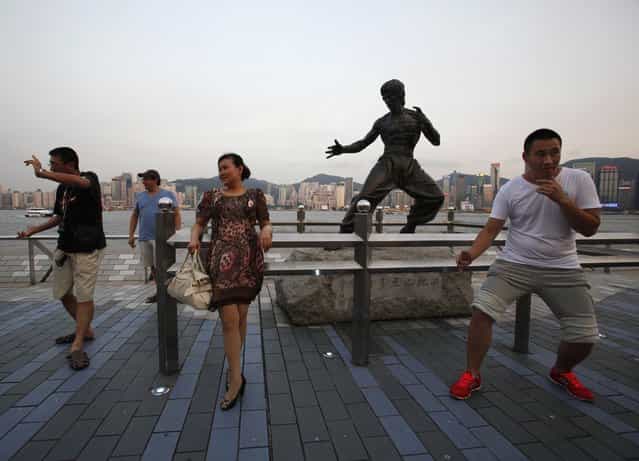 Tourists pose in front of a bronze statue of the late kung fu legend Bruce Lee on the waterfront facing Hong Kong island July 12, 2013. July 20 marks the 40th anniversary of the death of Lee, with a memorial event and exhibition to be held by his fan club and the government. (Photo by Bobby Yip/Reuters)