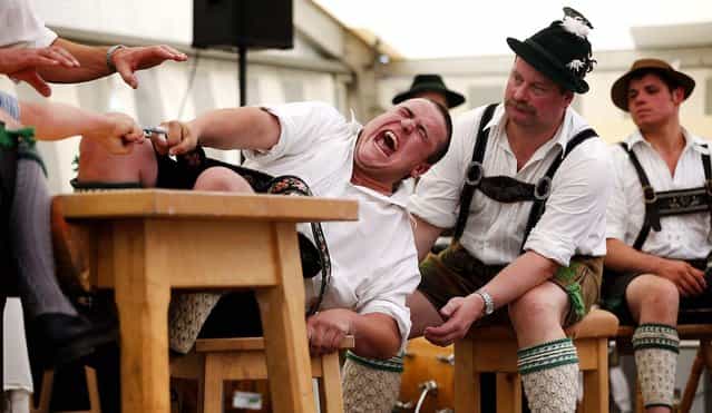 A man tries to pull his opponent over the table during the Alps Finger Wrestling championships in Mittenwald, Germany, on July 7, 2013. (Photo by Matthias Schrader/Associated Press)