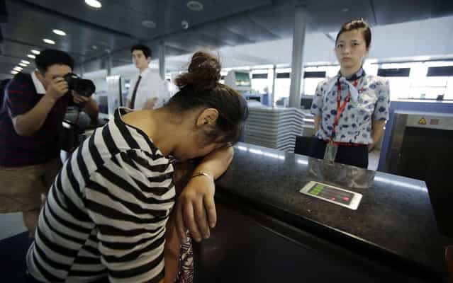 An unidentified family member of one of two Chinese students killed in a crash of Asiana Airlines' plane on Saturday, cries at the Airlines' counter as she and other family members check in a flight to San Francisco at Pudong International Airport in Shanghai, China, Monday, July 8, 2013. The Asiana flight crashed upon landing Saturday, July 6, at San Francisco International Airport, and the two of the 307 passengers aboard were killed. (Photo by Eugene Hoshiko/AP Photo)